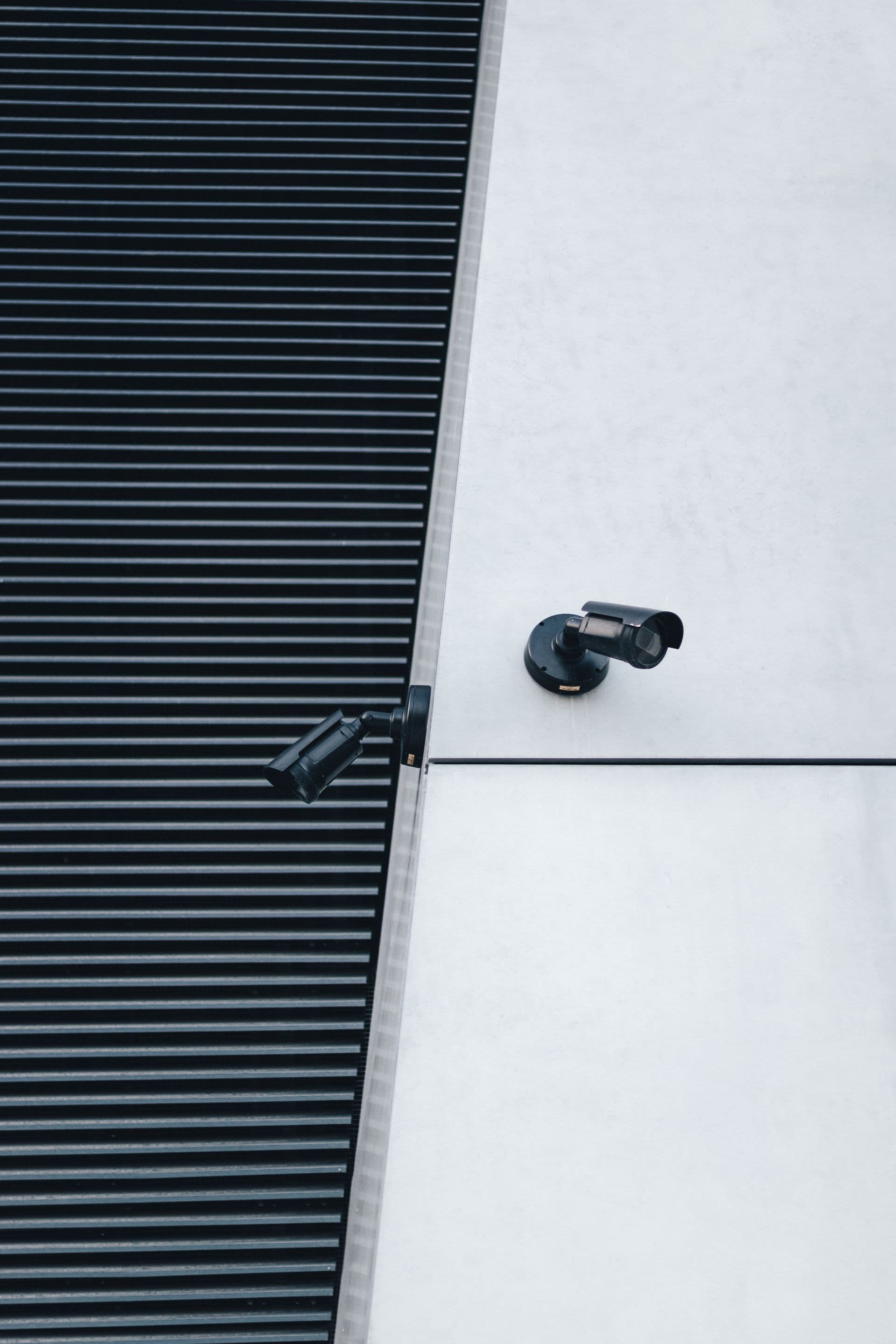 Deux caméras de surveillance fixées sur un mur blanc